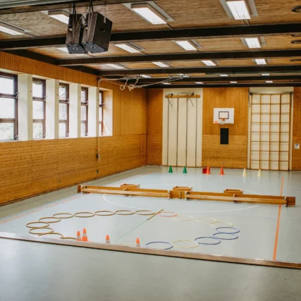 Turnhalle mit Bänken, Ringen und Hütchen.
