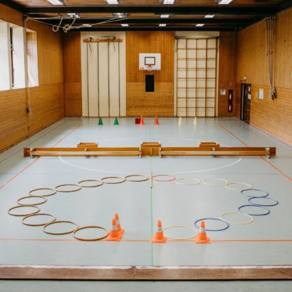 Turnhalle mit Bänken, Ringen und Hütchen.